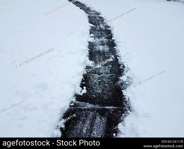 asphalt driveway with white snow and ice shoveling in winter