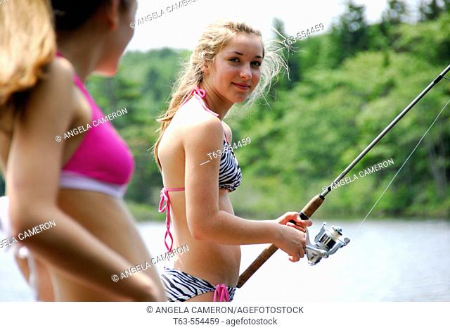 girl 18 looking at girl 13 fishing on dock at cottage