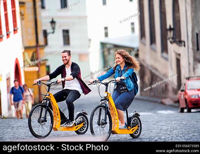 Young tourist couple travellers with electric scooters in small town, sightseeing