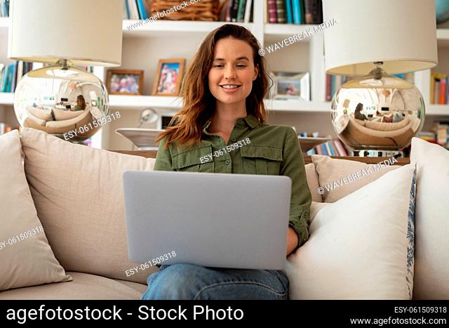 Woman using laptop while sitting on couch at home