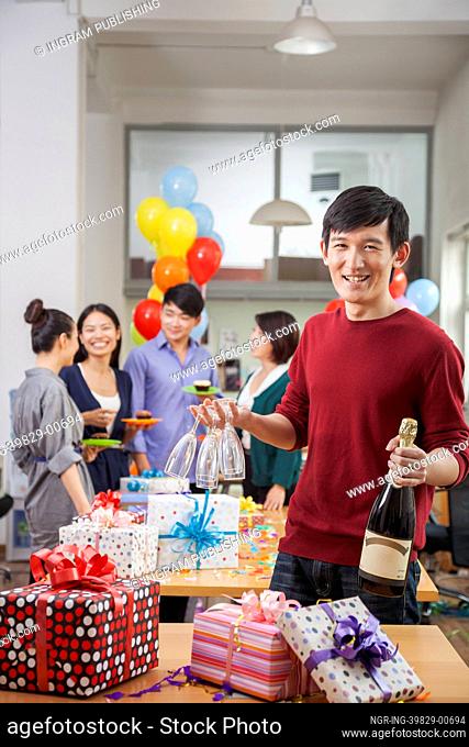Man Holding A Bottle Of Champagne and Glasses At Office Party