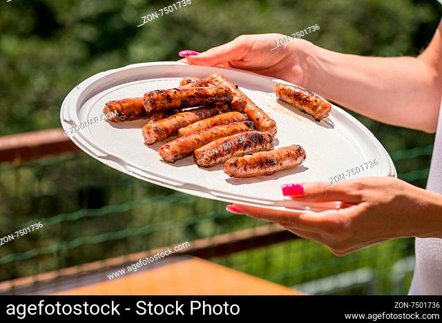 Pictured just cooked pork sausages issued in a plastic plate held by hand