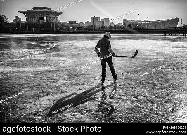 Hockey player on a frozen lake next to the Nest, National Stadium, the venue to hold the opening ceremony of the Winter Olympic Games in Beijing