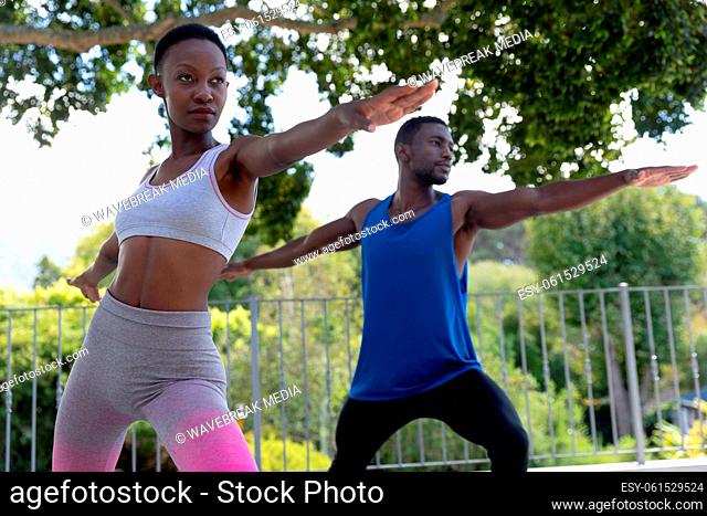 African american couple exercising practicing yoga on sunny garden terrace