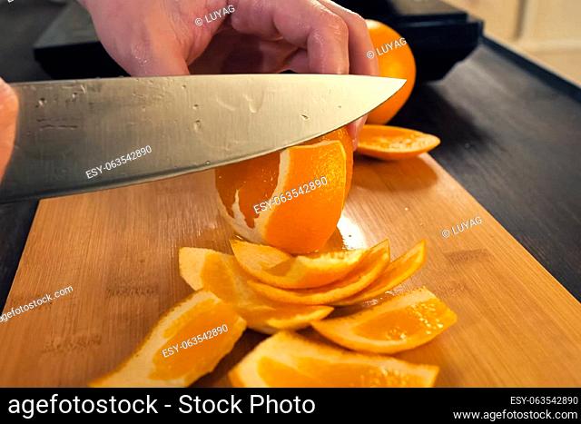 Cutting slices of oranges on a cutting board. Orange fruit with cutting board on brown wooden table