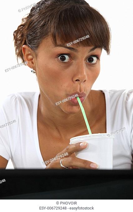 Woman drinking through a straw at work
