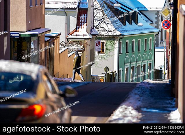 12 February 2021, Bavaria, Tirschenreuth: A woman crosses a street in Tirschenreuth. According to the Bavarian state government