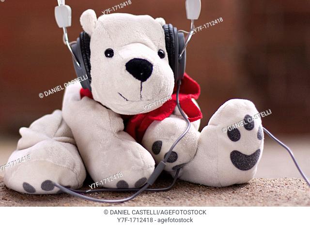 White teddy bear listening to music with headphones