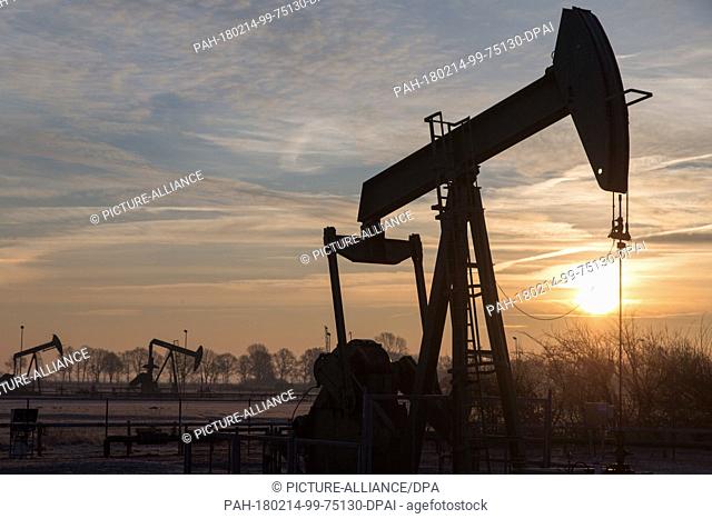 08 February 2018, Germany, Emlichheim: The sun rises behind a horsehead pump. For more than 70 years oil production has been running in the county of Bentheim