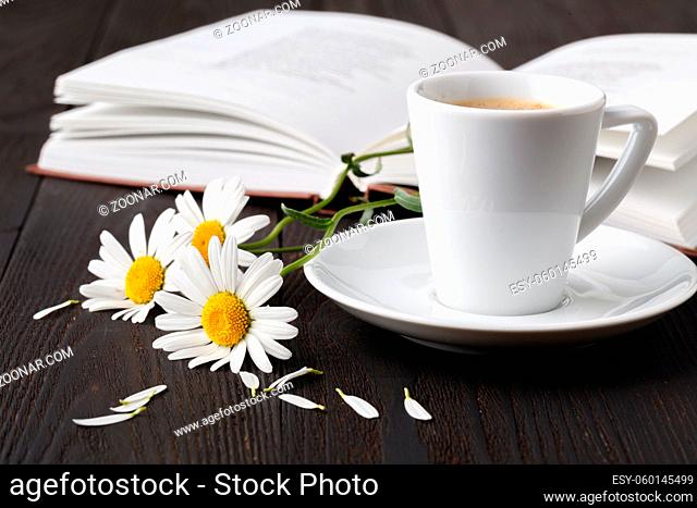 Stack of books with small bunch of daisies