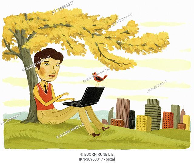 Businessman using laptop under tree