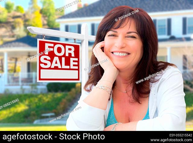 Middle Aged Woman In Front of House with For Sale Real Estate Sign In Yard