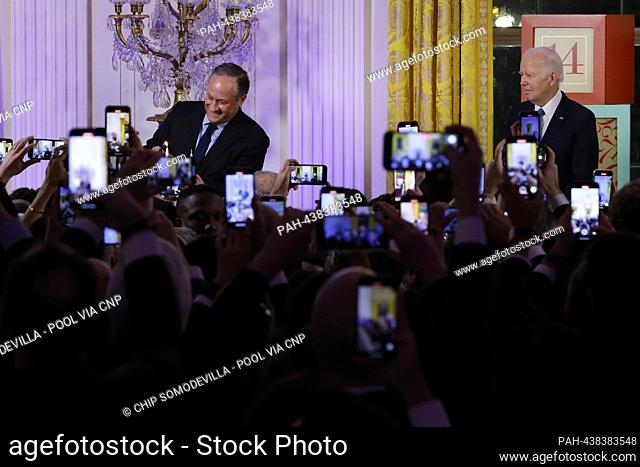 United States President Joe Biden (R) looks on as second gentleman Doug Emhoff lights the menorah during a Hanukkah holiday reception in the East Room of the...