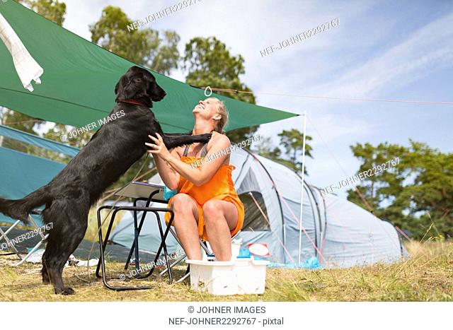 Young woman playing with dog at camping