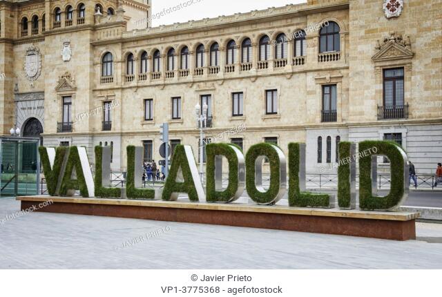 The name of the city of Valladolid written on a poster with plant letters appears in front of the façade of the Academia de Caballería, in the Zorrilla square