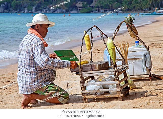 Beach vendor preparing corn on tiny portable barbecue on the island Ko Tao / Koh Tao, part of the Chumphon Archipelago in Southern Thailand
