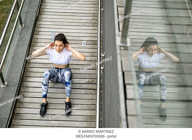 Young woman doing situps on a footbridge