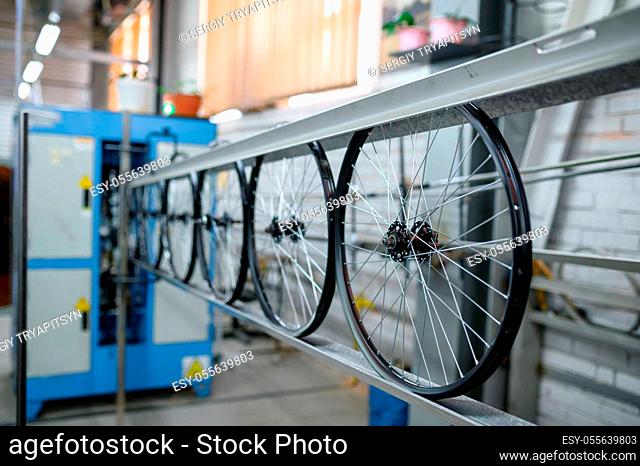 New aluminum bicycle wheels on assembly line, nobody. Bike parts on factory, cycle rims with hubs and spokes on machine, modern technology