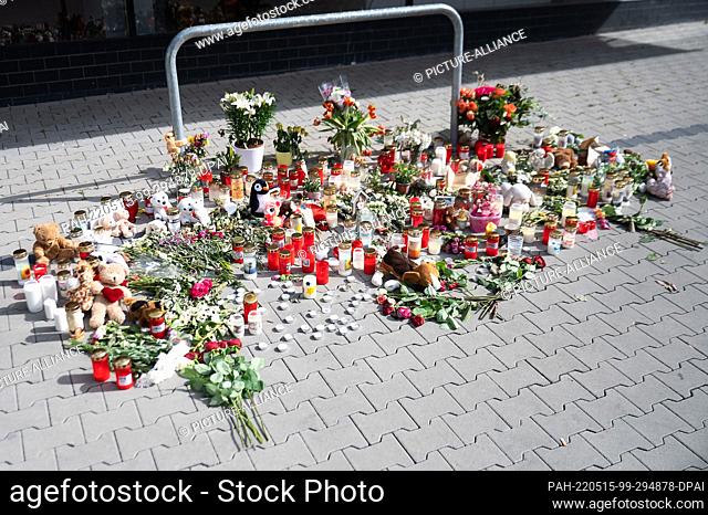 15 May 2022, Hessen, Hanau: Flowers, candles, stuffed animals and pictures lie outside the high-rise building where two children were killed on Wednesday