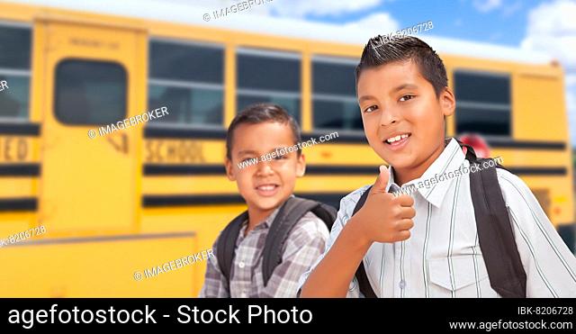 Young hispanic boys walking near school bus