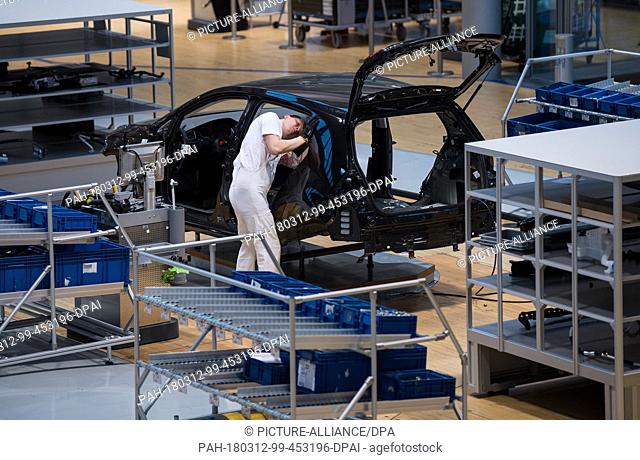 12 March 2018, Germany, Dresden: A Volkswagen employee works at the assembly of a VW e-Golf at the 'Glaeserne VW-Manufaktur' (lit