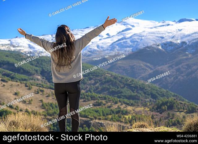 Latina woman on her back with arms outstretched happily enjoying the scenery outdoors in winter