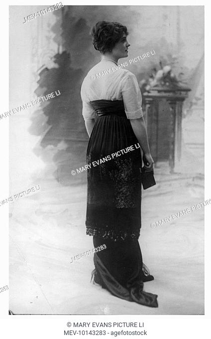 Column-like Directoire or Empire line revival: corsage of translucent fabric with a deep 'V' back, broad cummerbund & a narrow trained skirt with gathered tunic