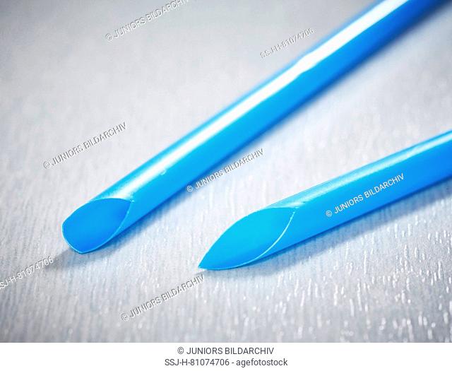 Two blue plastic drinking straws on gray background. Studio Picture