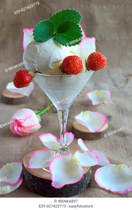 Ice cream with strawberries in a glass and rose petals on the table