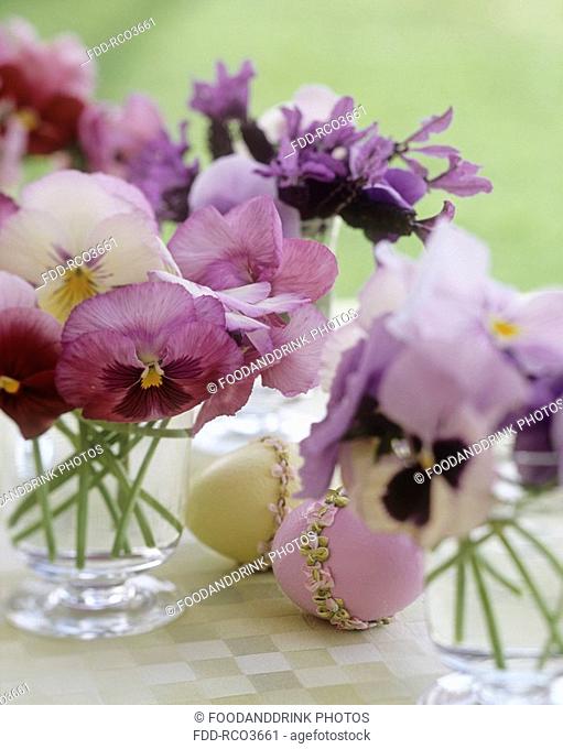 Arrangements of pansy flowers, pink and yellow decorated eggs