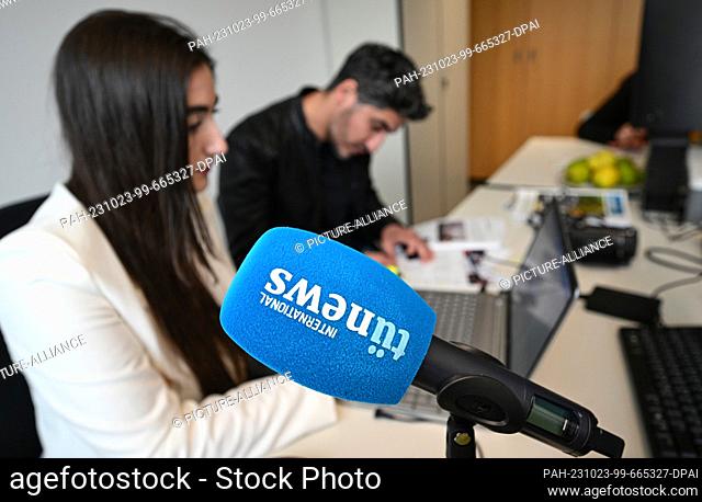 PRODUCTION - 19 October 2023, Baden-Württemberg, Tübingen: A microphone with the Tünews logo stands on a table. People who have fled their home countries work...