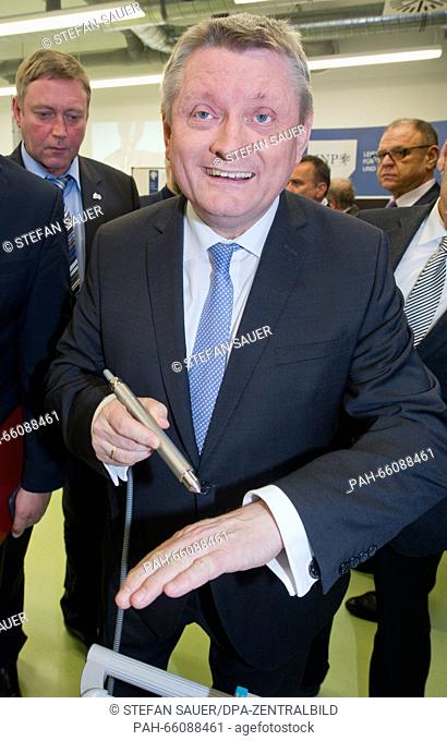 German federal health minister Hermann Groehe holds a silver plasma pen named 'KINPen' that emits a thin purple plasma beam in the new centre for diabetes...
