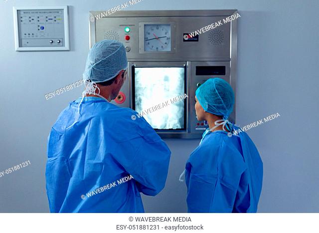 Surgeons examining x ray on x-ray light box at hospital