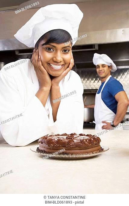 Mixed Race female pastry chef with cake