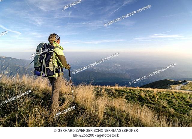 Female hiker carrying a backpack, view of the vast plain of the Piave river as seen from Col Visentin mountain, Italy, Europe