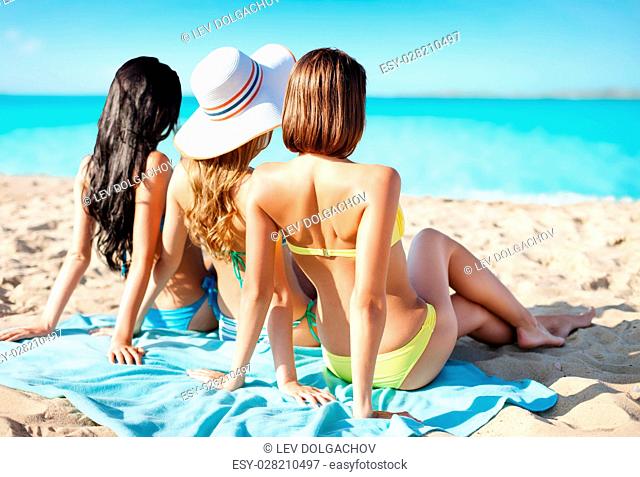 summer holidays, vacation, travel and people concept - group of women in swimwear sunbathing over exotic tropical beach background