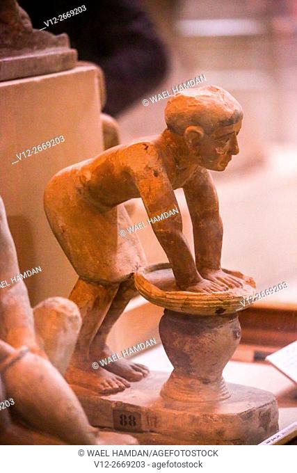 Figure of an Ancient Egyptian brewer pressing out fermented bread in a basket. Beer drained through into the pot beneath