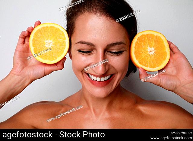 Beauty. Woman with radiant face skin squeezing orange in hand portrait. Beautiful smiling caucasian woman with natural makeup