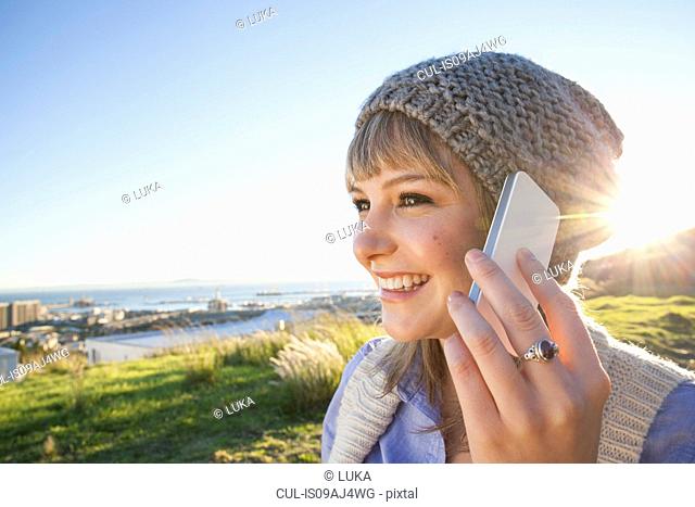Young woman chatting on smartphone, view of harbour in background, Cape Town, South Africa