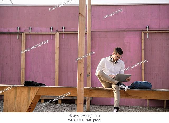 Young man sitting on platform using tablet