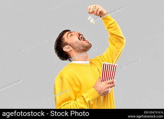 man in yellow sweatshirt eating popcorn
