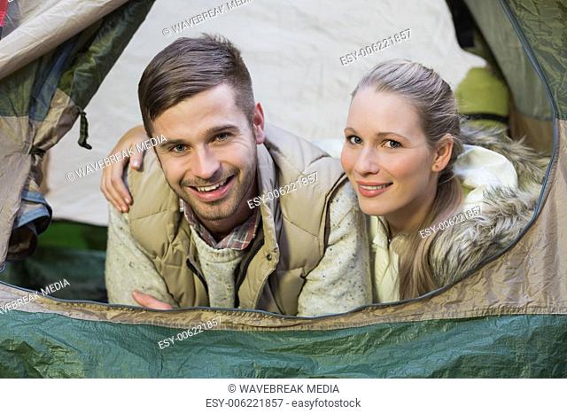 Smiling couple lying in tent after a hike