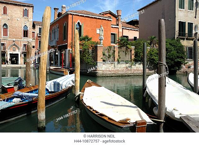 two canals meet in Venice, overlooked by an ancient statue. boats are parked around the crossing and beautiful venetian houses line the waterways