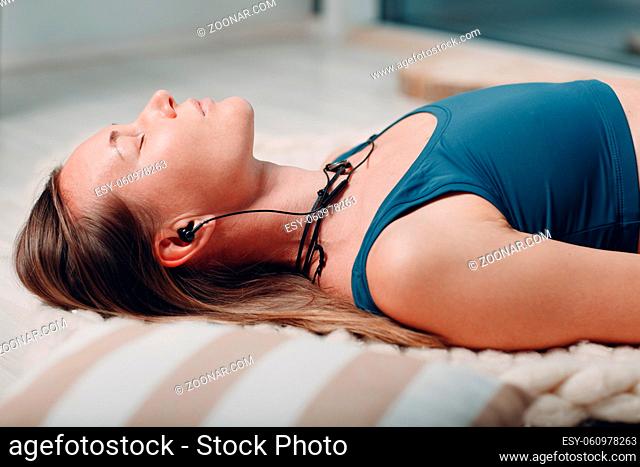 Adult mature woman doing yoga nidra and lay at home with online tutorials on laptop