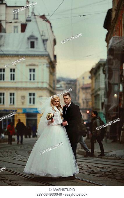 Happy couple of newlywed valentynes posing in old european street