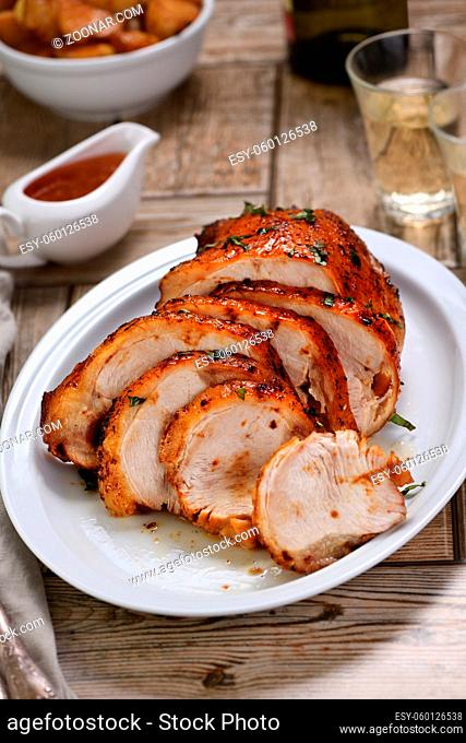 Sliced into slices baked turkey breast underneath sour- sweet  sauce at the dinner table