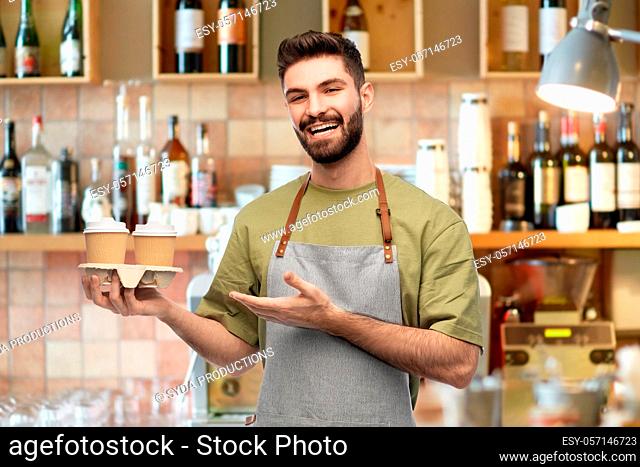 happy smiling barman in apron with takeaway coffee
