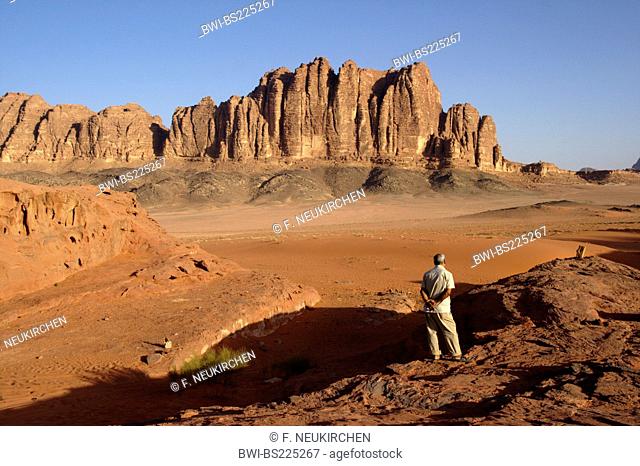 single man standing on a rock looking at the desert Wadi Rum, Jordan