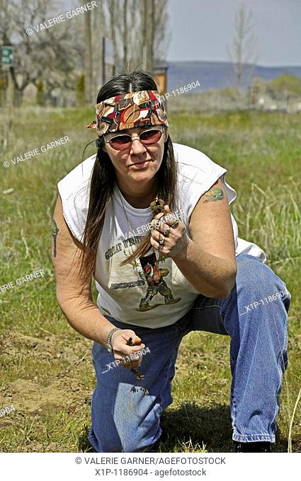 his mature Native American Indian woman with long hair and a headband has dug and is showing Camas sweet potatoes roots Camas is a traditional Native American...