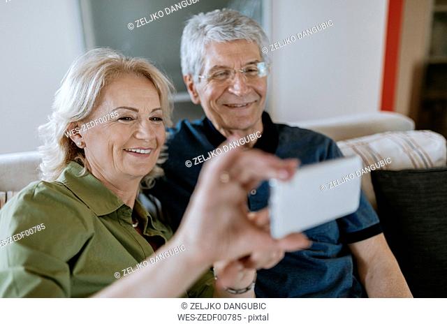 Senior couple at home sitting on couch taking a selfie